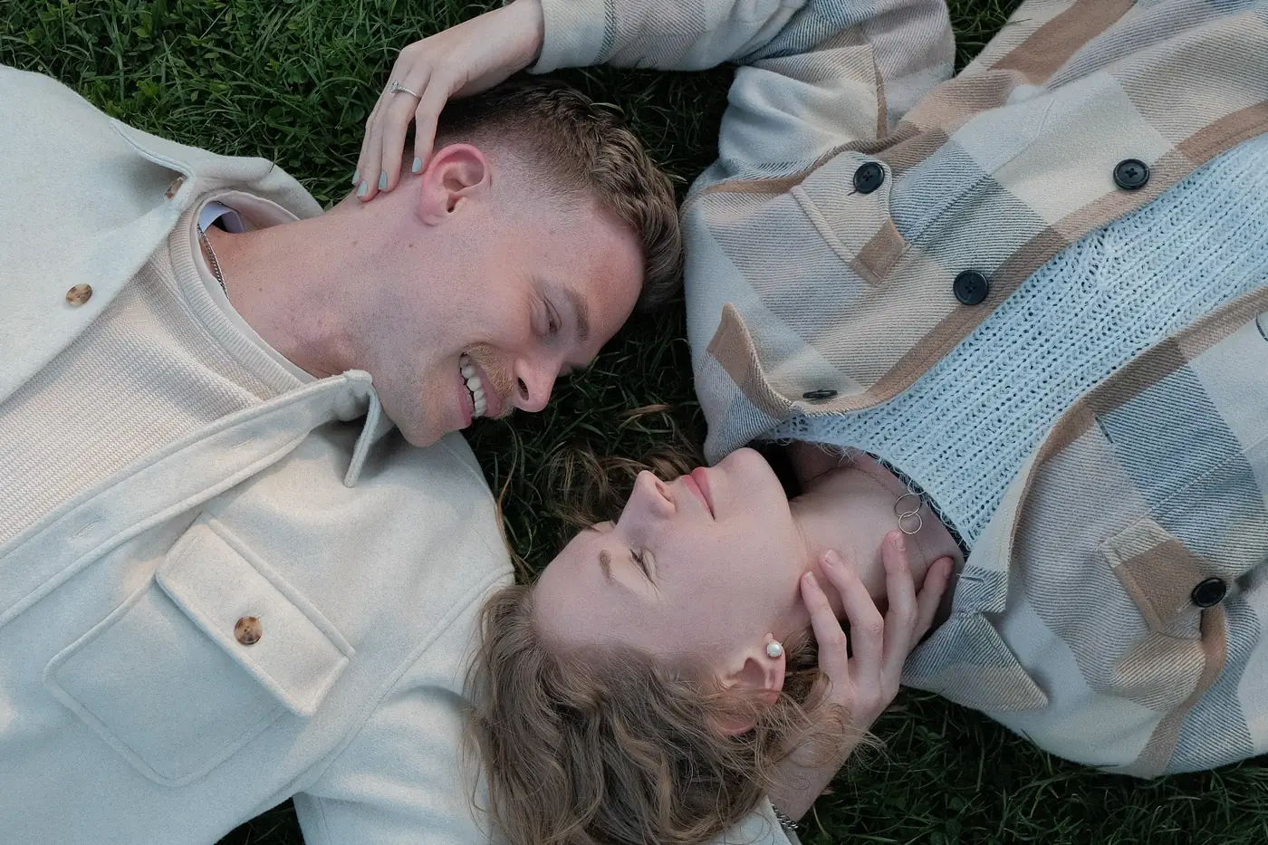 Couple lying head to head in the grass, seen from above