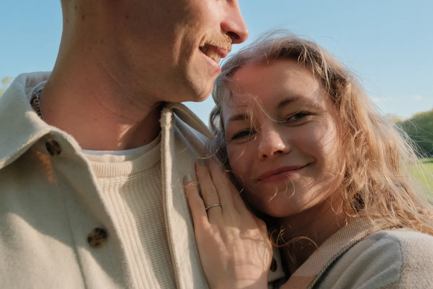 Close-up of her cheek resting on his shoulder, smiling at the camera