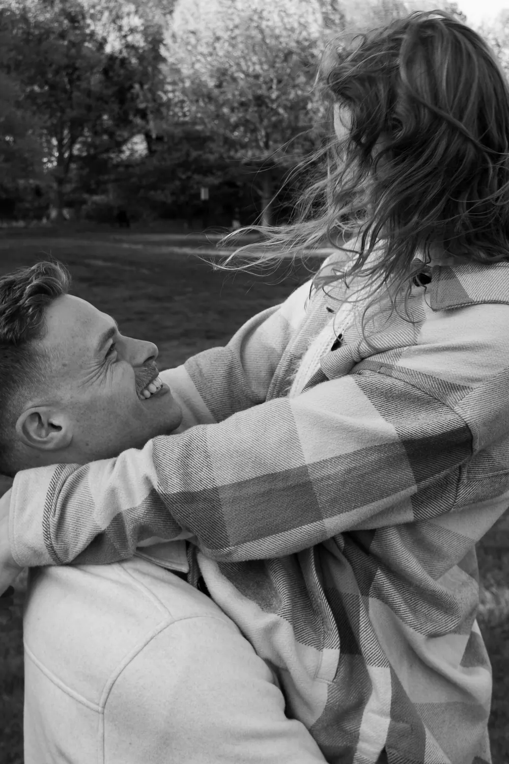 Black-and-white moment of him lifting her in the park