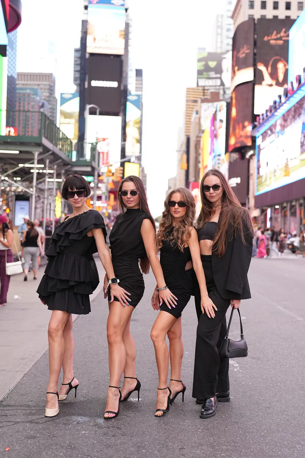 Four friends in sunglasses posing in a line in Times Square