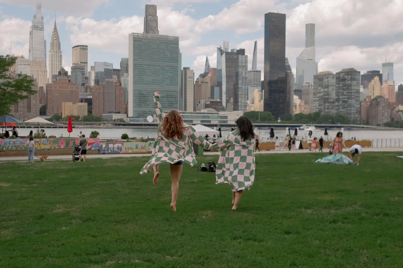 Two friends in checkered robes running barefoot toward the skyline, one arm raised