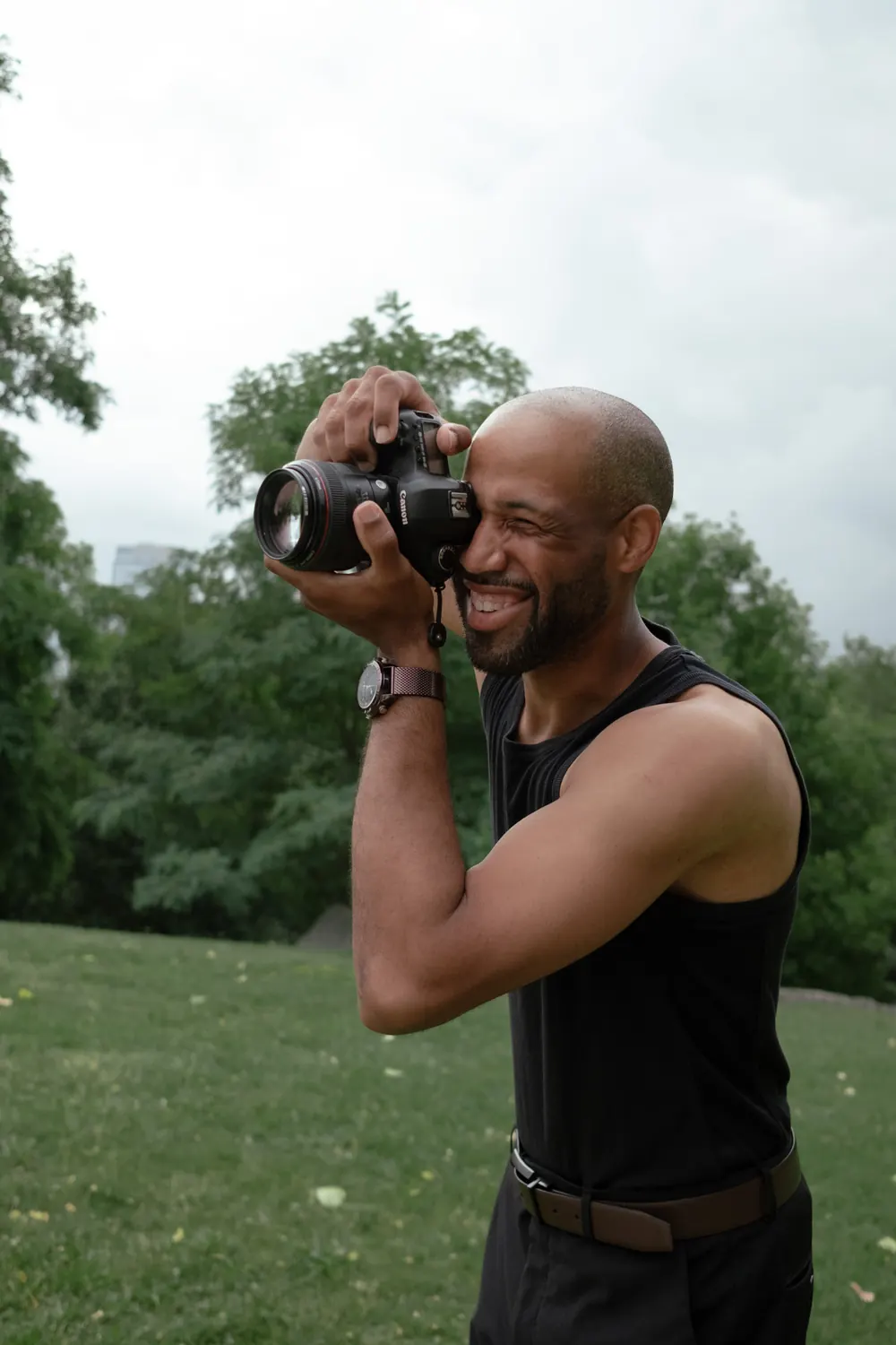 Man laughing while taking a photo in a park