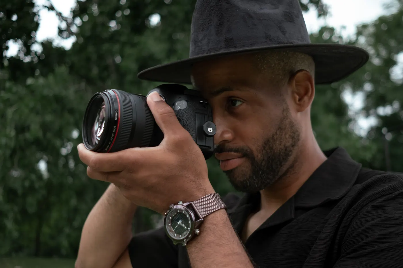 Man in a black hat looking through a camera viewfinder